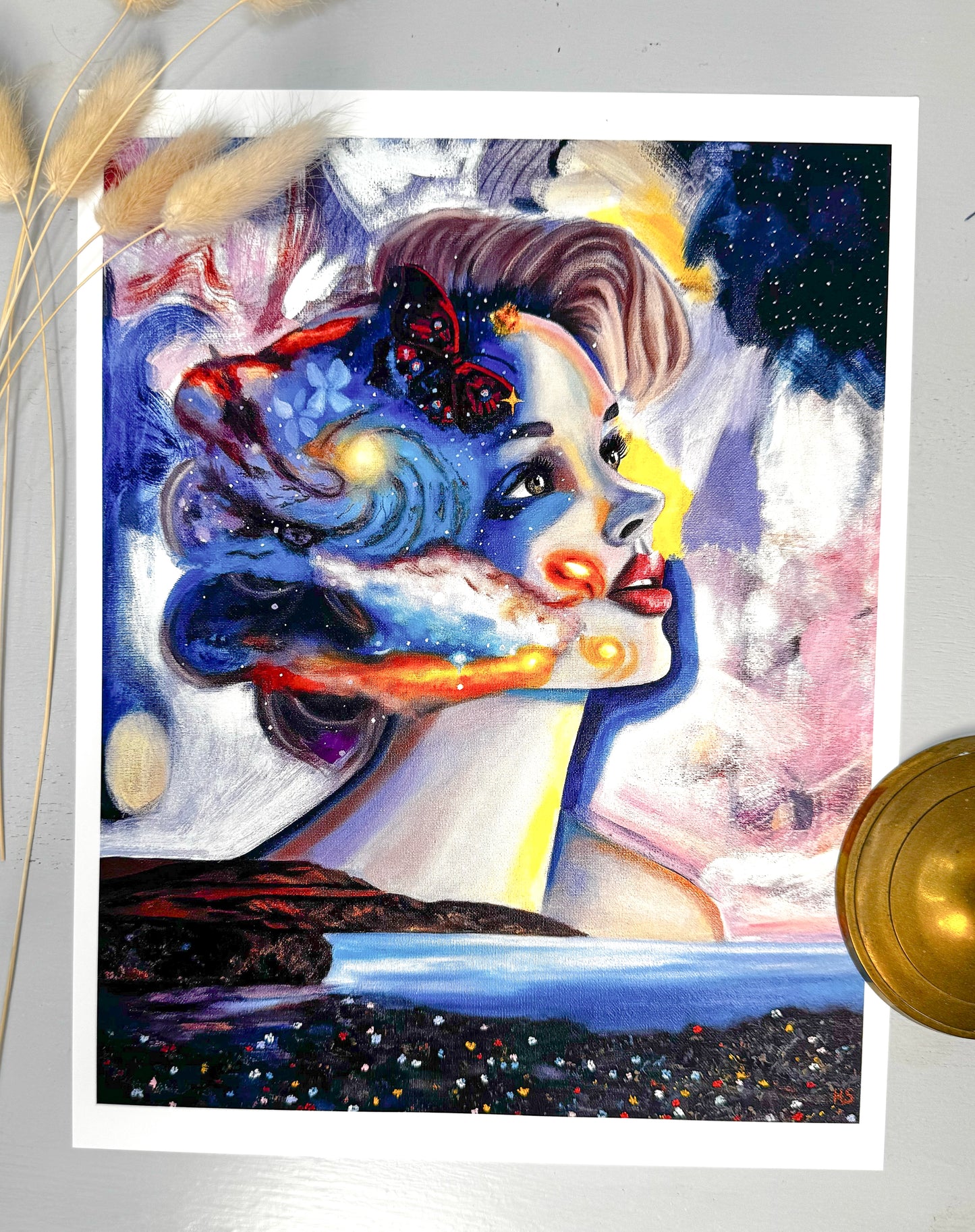 Colorful abstract art print of a woman's face with artistic elements a starry night sky, a galaxy, red butterfly and a field of tiny flowers a white background.