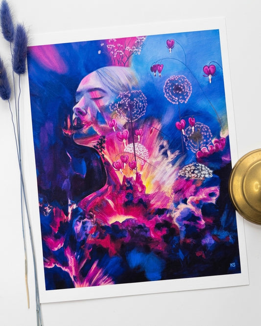A picture of a print of a woman surrounded by bleeding hearts and colourful bursts of swatches of paint. Mostly blue and pink