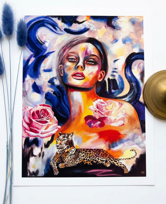 A picture of an art print with a woman, a galaxy a cheetah and blue vibrant swatches of paint.