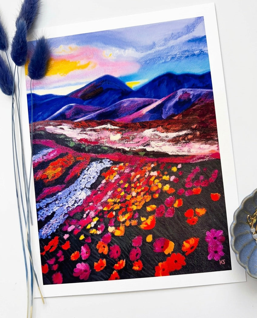 A print of a landscape featuring blue mountains, and a field of red flowers