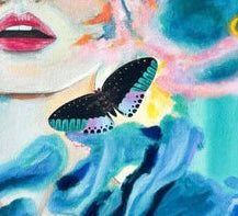 A close up of a painted moth and part of a woman’s face with blue clouds or water