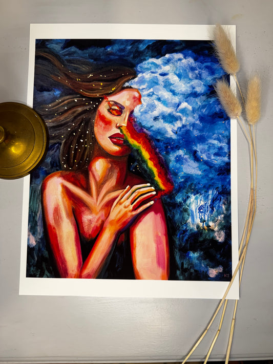 Artistic depiction of a woman with a rainbow across her face in a moody blue sky and gold flecks in her hair.