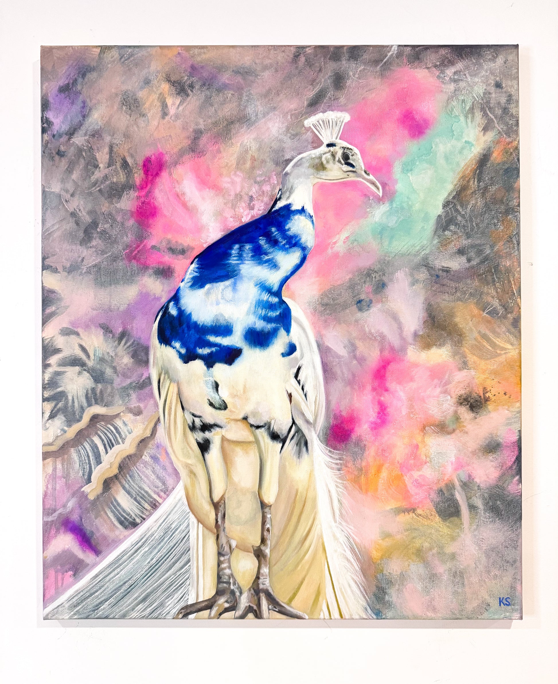 A colorful painting of a peacock with a vivid blue back and cream-colored body, set against a dreamy abstract background of pink, purple, and teal brushstrokes.