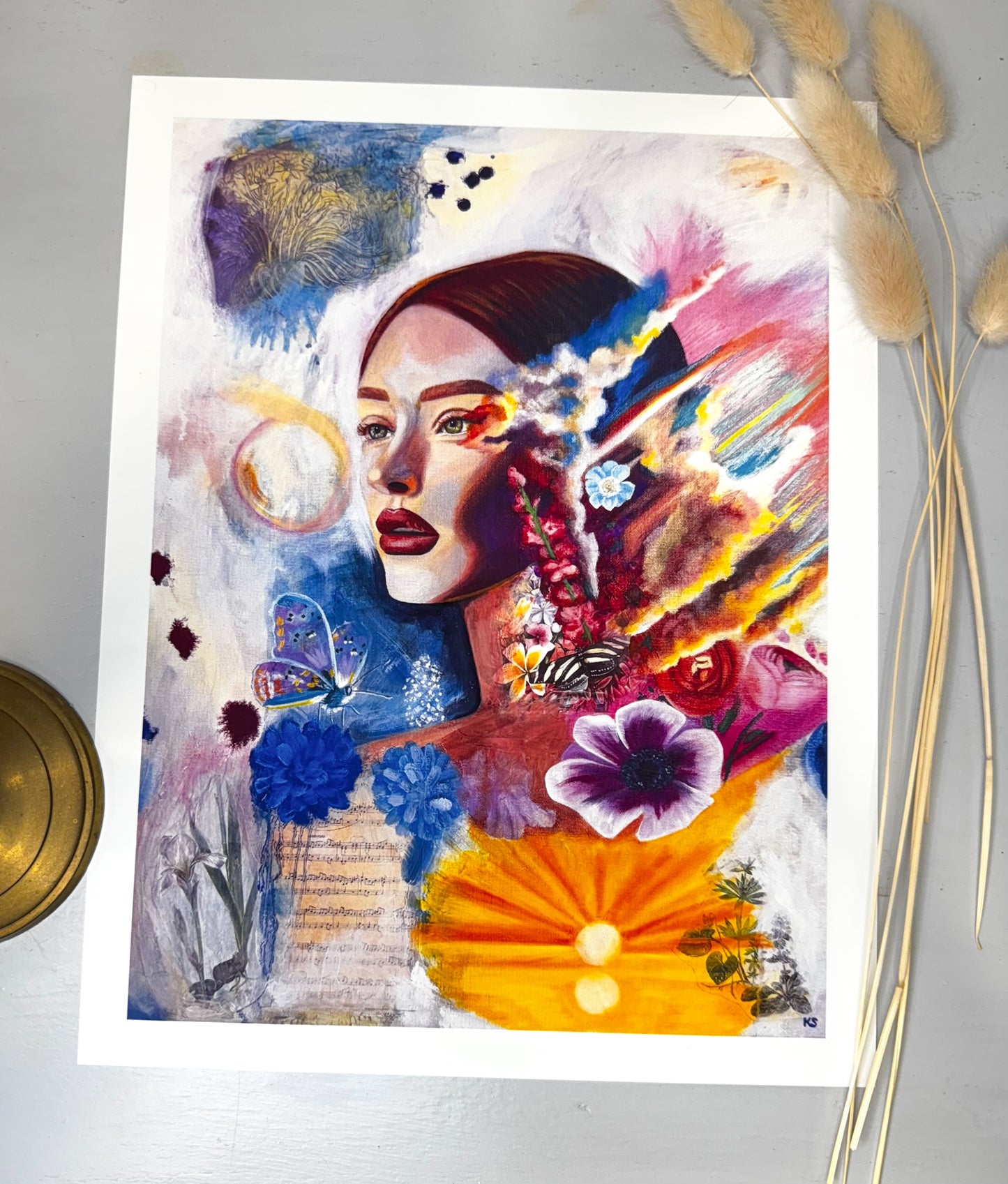Colorful art print of a woman with flowers and butterflies, flames and a sunset on a white background