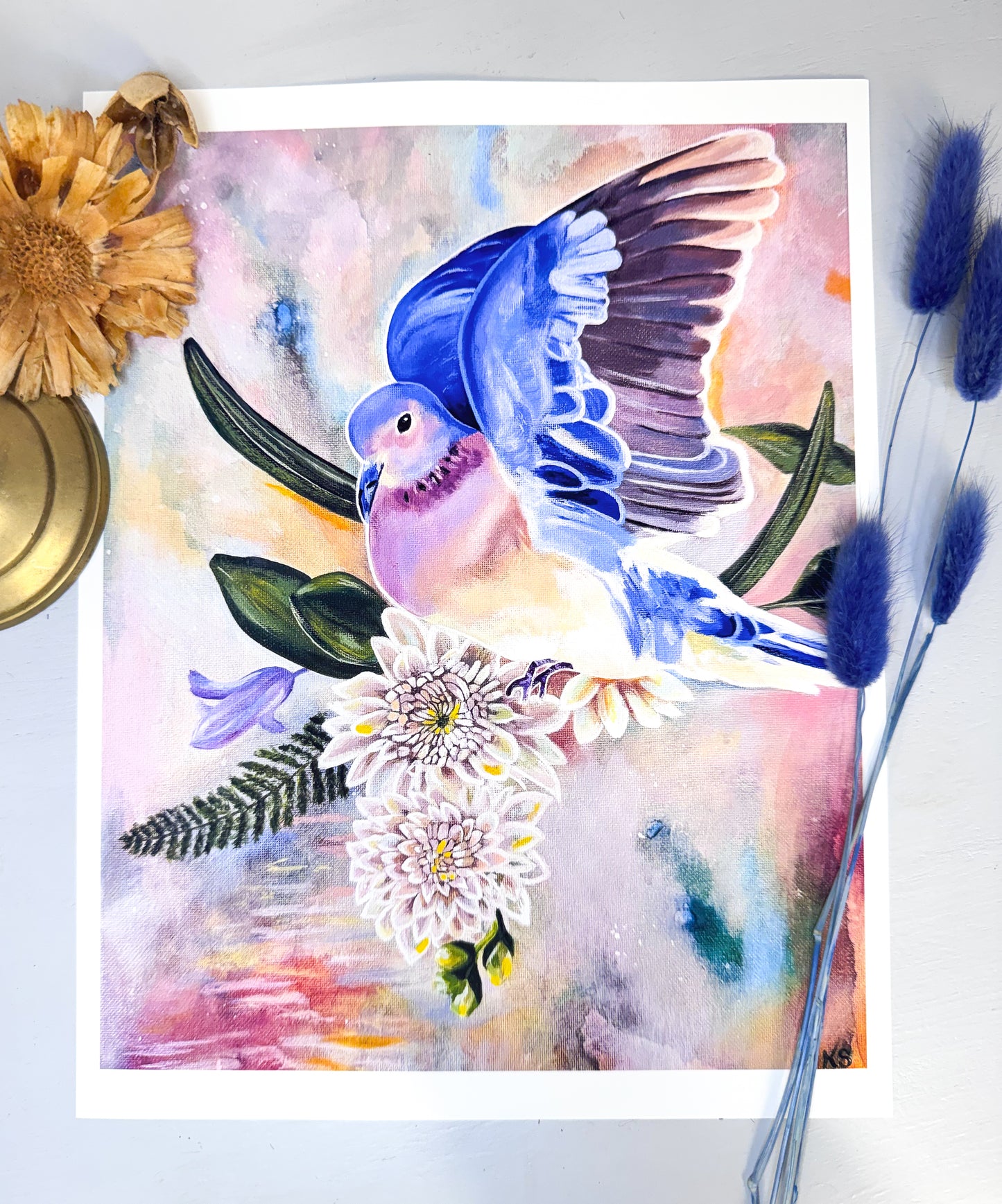 A print featuring a blue dove against a soft abstract background with flowers and blades of grass.