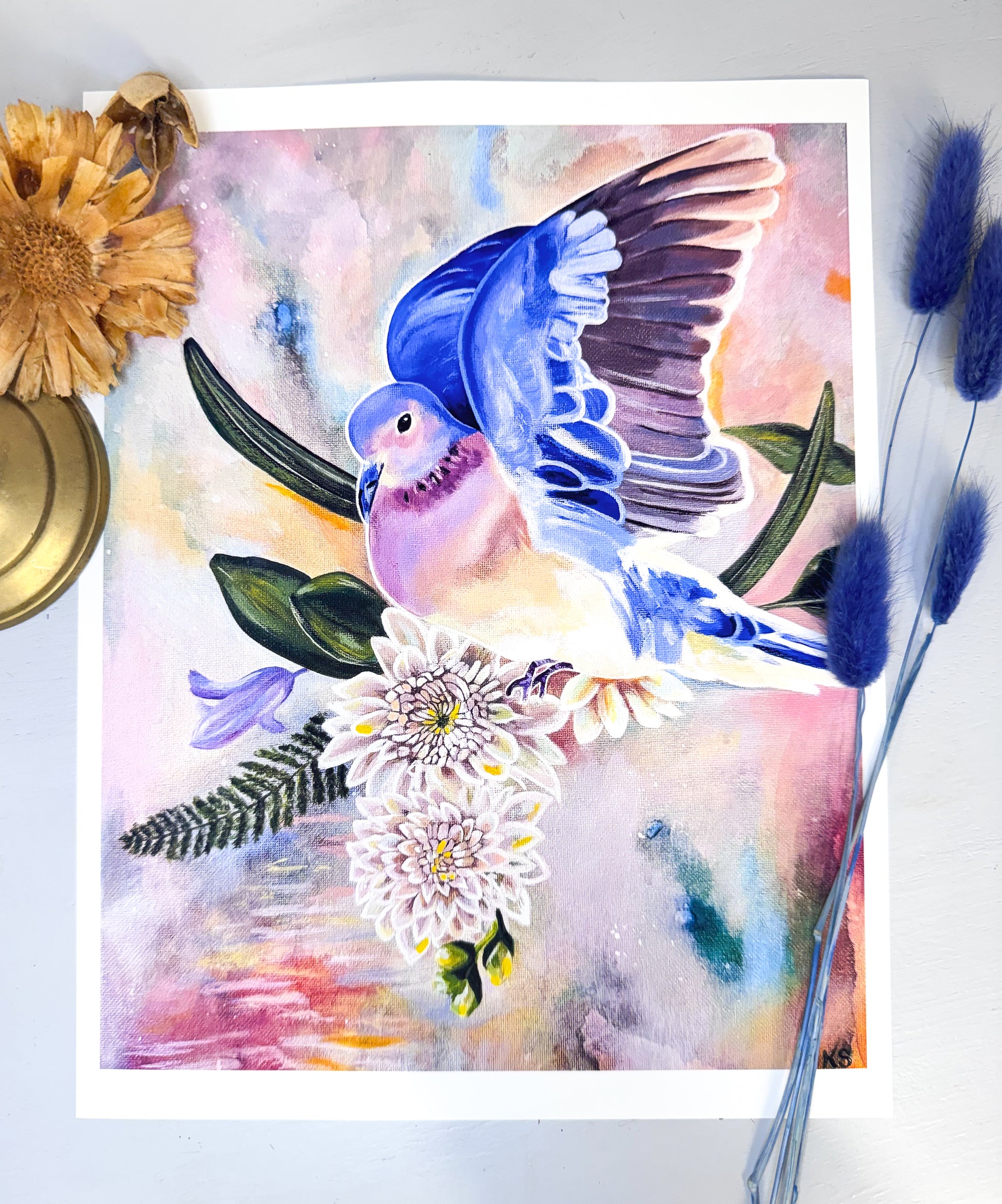 A print featuring a blue dove against a soft abstract background with flowers and blades of grass.