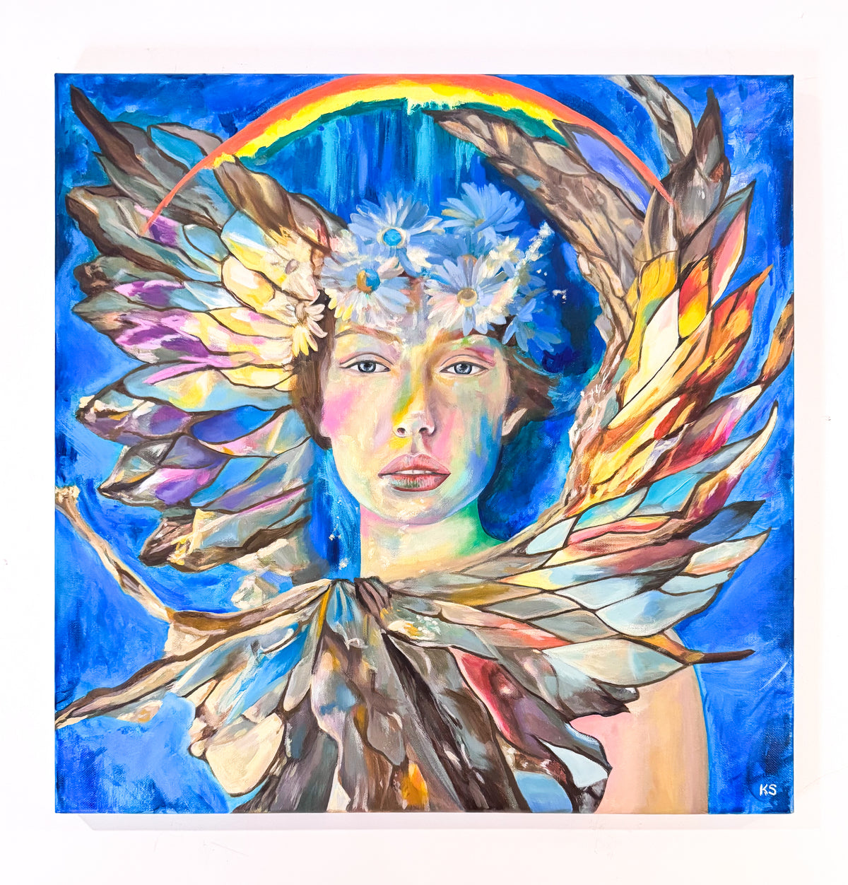 A picture of a painting featuring a portrait of a woman surrounded by a circle Of wings against a blue background.